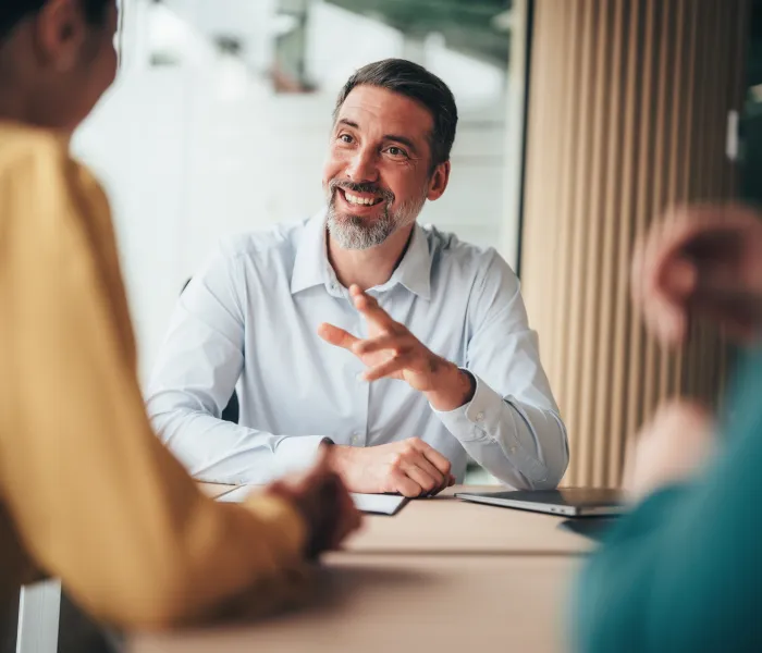 Manager speaking with two colleagues during an office meeting