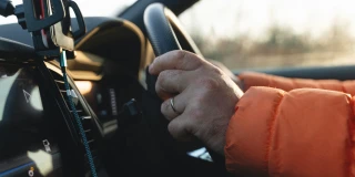 Close-up of a driver’s hands on the steering wheel beside a mounted smartphone