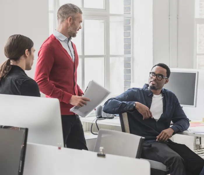 Three colleagues discussing documents in a bright office